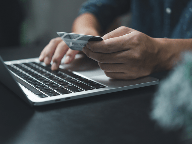 Person som ser på bankkortet sitt og ser på PC